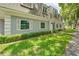 Exterior view of townhome featuring well-manicured lawn and gray paint with white trim at 1710 Belleair Forest Dr # A, Belleair, FL 33756