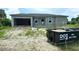 Unfinished house with a visible gray exterior, window frames, and a dumpster at 18581 Lake Worth Blvd, Port Charlotte, FL 33948