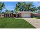 Charming single-story brick home with a lush green lawn, palm trees, and a two-car garage at 2138 Viola Dr, Clearwater, FL 33764
