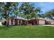 Well-maintained brick home featuring a green lawn, mature trees and manicured landscaping at 2138 Viola Dr, Clearwater, FL 33764