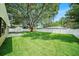 A sprawling backyard featuring a large lawn, mature trees, white vinyl fencing, and a concrete patio at 3072 Sugar Bear Trl, Palm Harbor, FL 34684