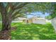 Spacious backyard with a well-maintained lawn, mature trees, patio set with umbrella, and white vinyl fencing at 3072 Sugar Bear Trl, Palm Harbor, FL 34684