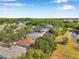 An aerial view shows a single Gathering home with brown roof, a pond, and green trees in a lovely neighborhood at 3230 Bellericay Ln, Land O Lakes, FL 34638