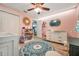 Adorable Bedroom with a crib, dresser, ceiling fan, and a round blue patterned rug at 3230 Bellericay Ln, Land O Lakes, FL 34638
