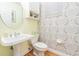 Powder room featuring a pedestal sink, patterned wallpaper, and wood-look flooring at 350 2Nd N St # 1, St Petersburg, FL 33701
