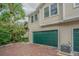 Garage exterior view with a green door, brick driveway, and beautiful landscaping featuring flowering bushes and a palm tree at 350 2Nd N St # 1, St Petersburg, FL 33701