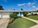 Well-manicured front yard with lush lawn and a blue door single-story home at 3701 Manatee Se Dr, St Petersburg, FL 33705