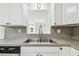 Close up of kitchen sink with stainless steel fixtures, gray countertop and white cabinets at 3818 Grove S St, St Petersburg, FL 33705
