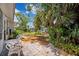 Backyard features a brick paved patio, white outdoor furniture, and lush, tropical landscaping at 4229 Glissade Dr, New Port Richey, FL 34652