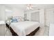 Bright bedroom with tile flooring, white walls, a large bed with blue accent pillows, and ample closet space at 4229 Glissade Dr, New Port Richey, FL 34652