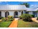 Charming home exterior featuring white walls, a metal roof, arched doorways, and vibrant landscaping at 4229 Glissade Dr, New Port Richey, FL 34652