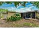 View of the backyard with a screened-in porch, a blue bench, and plants at 4411 W Bay Villa Ave, Tampa, FL 33611