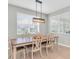 Bright dining room featuring a long wooden table and six chairs under a modern pendant light fixture at 4496 Tatum Loop, Odessa, FL 33556