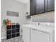 Functional laundry room with black cabinets and black and white patterned floors at 4496 Tatum Loop, Odessa, FL 33556