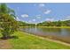 Scenic backyard featuring a serene lake view, lush greenery, and mature trees at 4830 Grand Banks Dr, Wimauma, FL 33598