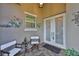 Inviting front porch area featuring tiled flooring, seating, and decorative wall art near the double-door entry at 4830 Grand Banks Dr, Wimauma, FL 33598