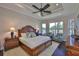 Serene main bedroom with tray ceiling, water view windows and dark wood floors at 4830 Grand Banks Dr, Wimauma, FL 33598