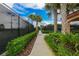 Community tennis court enclosed by black fencing, with tropical landscaping and palm trees at 4830 Grand Banks Dr, Wimauma, FL 33598