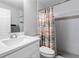 Bright bathroom features a modern sink, faucet, patterned shower curtain, and white tiled walls at 4852 Trinidad Dr, Land O Lakes, FL 34639