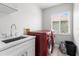 Bright laundry room with a sink, folding counter, red washer and dryer, and a window at 4852 Trinidad Dr, Land O Lakes, FL 34639