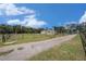 A home's exterior with a long driveway, grassy yard, and trees under a blue sky filled with clouds at 5012 Troydale Rd, Tampa, FL 33615