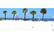 Sandy beach scene with palm trees, lifeguard station, colorful umbrellas, and the ocean in the background at 6334 Spring Flower Dr # 24, New Port Richey, FL 34653