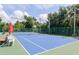 Well-maintained tennis court featuring a net, surrounding fence, and seating area with an umbrella at 6334 Spring Flower Dr # 24, New Port Richey, FL 34653