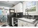 Bright kitchen with white cabinets, a black refrigerator, and black and white checkered flooring at 634 6Th N St, St Petersburg, FL 33701
