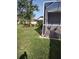 A view of well-maintained backyard with a screened enclosure, lush green lawn, and landscaped garden beds at 6615 Vanda Ln, Land O Lakes, FL 34637