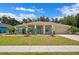 Charming single-story home with a well-manicured lawn, vibrant turquoise accents, and a welcoming front porch at 6724 Clair Shore Dr, Apollo Beach, FL 33572