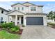 Charming two-story home featuring a gray garage door, a welcoming front porch, and well-maintained landscaping at 718 W Kentucky Ave, Tampa, FL 33603