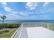 Scenic deck with white railing offering views of the ocean, palm trees and blue skies at 812 Point Seaside Dr, Crystal Beach, FL 34681