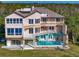 Back of home featuring a private pool, balconies, and stairs to each level, set on a sprawling lawn at 812 Point Seaside Dr, Crystal Beach, FL 34681
