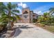 Front view of a multi-story home with an elaborate driveway, mature trees, and immaculate landscaping at 812 Point Seaside Dr, Crystal Beach, FL 34681
