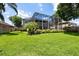 Spacious backyard with a healthy green lawn, well-maintained landscaping, screened in patio, and mature trees at 9223 Brindlewood Dr, Odessa, FL 33556