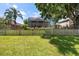 Large backyard with a picket fence, lush green lawn, mature trees, and a screened-in patio for outdoor enjoyment at 9223 Brindlewood Dr, Odessa, FL 33556