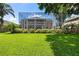 Large backyard with a manicured lawn, screened-in patio, lush green landscaping and mature trees at 9223 Brindlewood Dr, Odessa, FL 33556