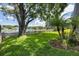Expansive green backyard with mature trees, a picket fence and a serene lake with a fountain at 9223 Brindlewood Dr, Odessa, FL 33556