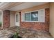 Covered porch with brick accent wall and tile flooring, providing a welcoming entrance to the home at 9810 N 53Rd St, Temple Terrace, FL 33617