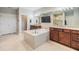 Bright bathroom featuring a large tub, double sinks, a wall-mounted television, and glass shower at 10313 Scarlet Chase Dr, Riverview, FL 33569