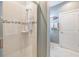 Shower with clear glass doors, features tile surround with built-in shelving and a handheld showerhead at 10313 Scarlet Chase Dr, Riverview, FL 33569