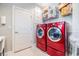 Laundry room featuring a stacked red washer and dryer set, white door, and storage shelves at 10313 Scarlet Chase Dr, Riverview, FL 33569