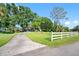 Scenic view of a home with a long driveway, white fence, and beautiful mature trees at 11109 Winn Rd, Riverview, FL 33569