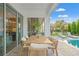 A cozy outdoor dining area with a wood table and seating next to a pool and sliding glass doors at 13859 Sharp Hawk Dr, Riverview, FL 33569