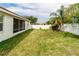 Lush backyard with green lawn, white fence, and screened-in lanai, offering a private outdoor retreat at 14027 Bensbrook Dr, Spring Hill, FL 34609