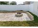 Paver patio with a decorative stone firepit surrounded by a low wall, grass, and a white vinyl fence at 14027 Bensbrook Dr, Spring Hill, FL 34609