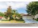 Attractive single-story home featuring mature trees, a well-manicured lawn, and an attached two-car garage at 14027 Bensbrook Dr, Spring Hill, FL 34609