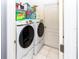 Well-organized laundry room showcasing side-by-side Samsung washer and dryer, with shelving for storage and tile flooring at 14027 Bensbrook Dr, Spring Hill, FL 34609