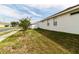 An exterior view of the side yard features green grass, street view, and a glimpse of the home's architecture at 14027 Bensbrook Dr, Spring Hill, FL 34609