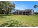 Sprawling lawn leading to home, complete with screen enclosed patio, and lovely landscaping at 14181 Cornewall Ln, Spring Hill, FL 34609